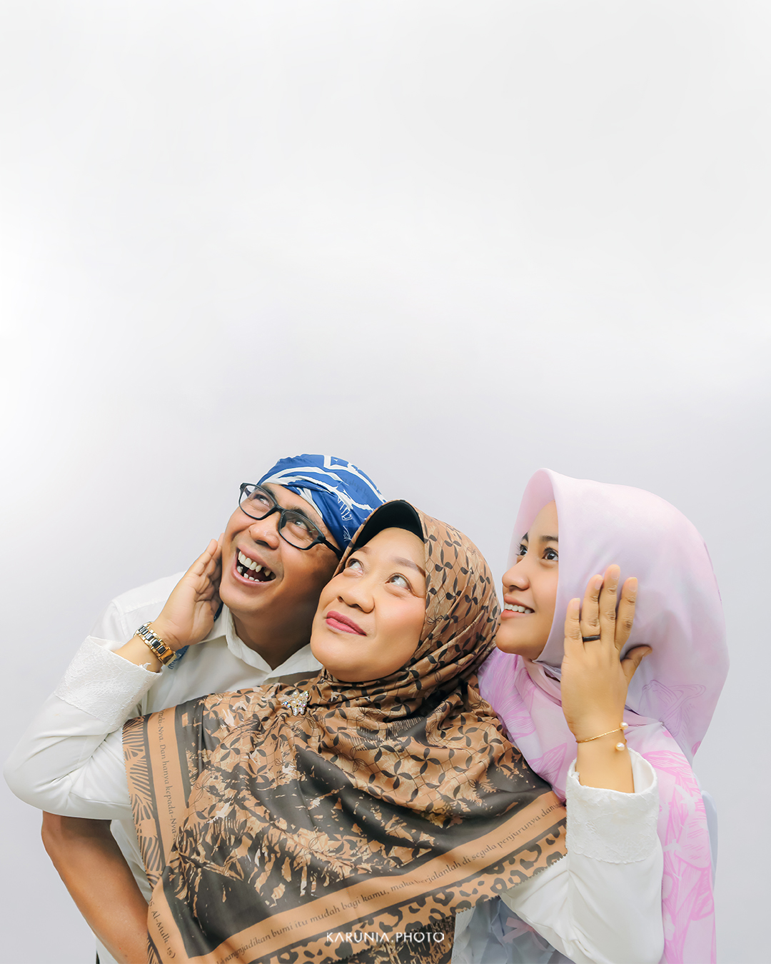 Three siblings sitting on wooden steps in coordinating outfits with genuine smiles and relaxed poses